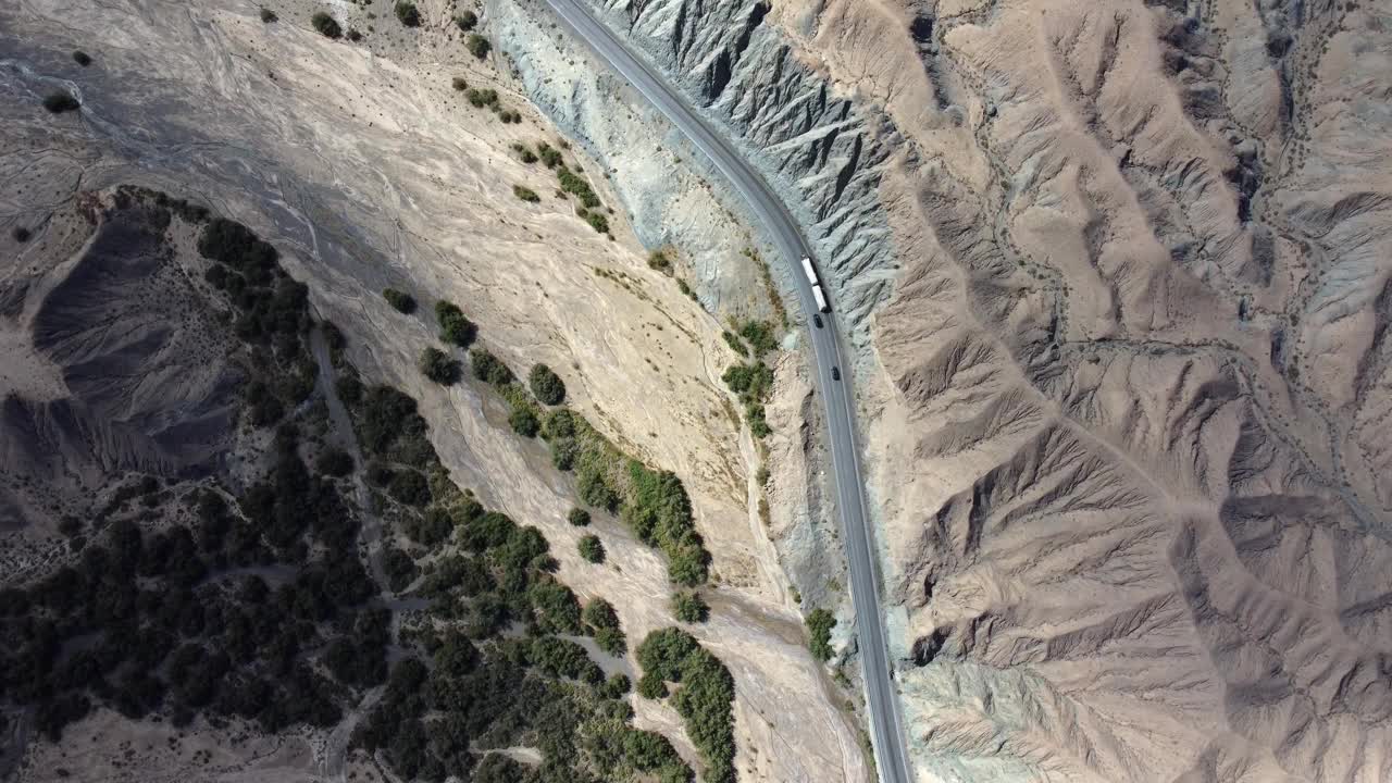 航拍视频显示汽车行驶在被干燥的沙漠岩石山脉包围的道路上视频素材