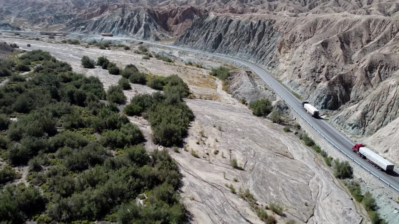 航拍视频显示汽车行驶在被干燥的沙漠岩石山脉包围的道路上视频素材