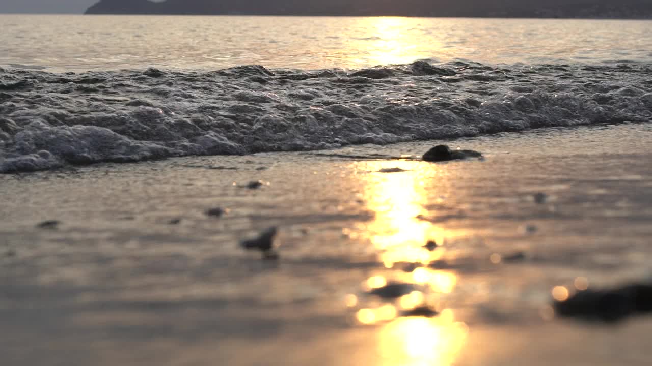 在萨索斯，海浪在日落时溅在海滩上视频素材