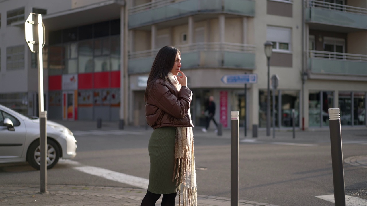 一个沉思的年轻女子站在城市的街道上思考。20多岁的成年女孩站在城市环境的户外，带着深思的表情视频素材