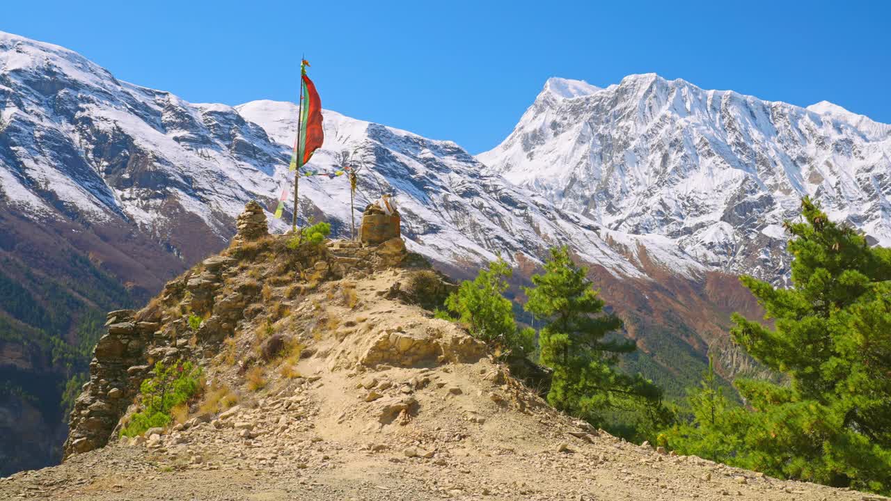 尼泊尔安纳普尔纳环形山，向迎风飘扬的经幡走向山峰，远处是陡峭的雪山视频素材