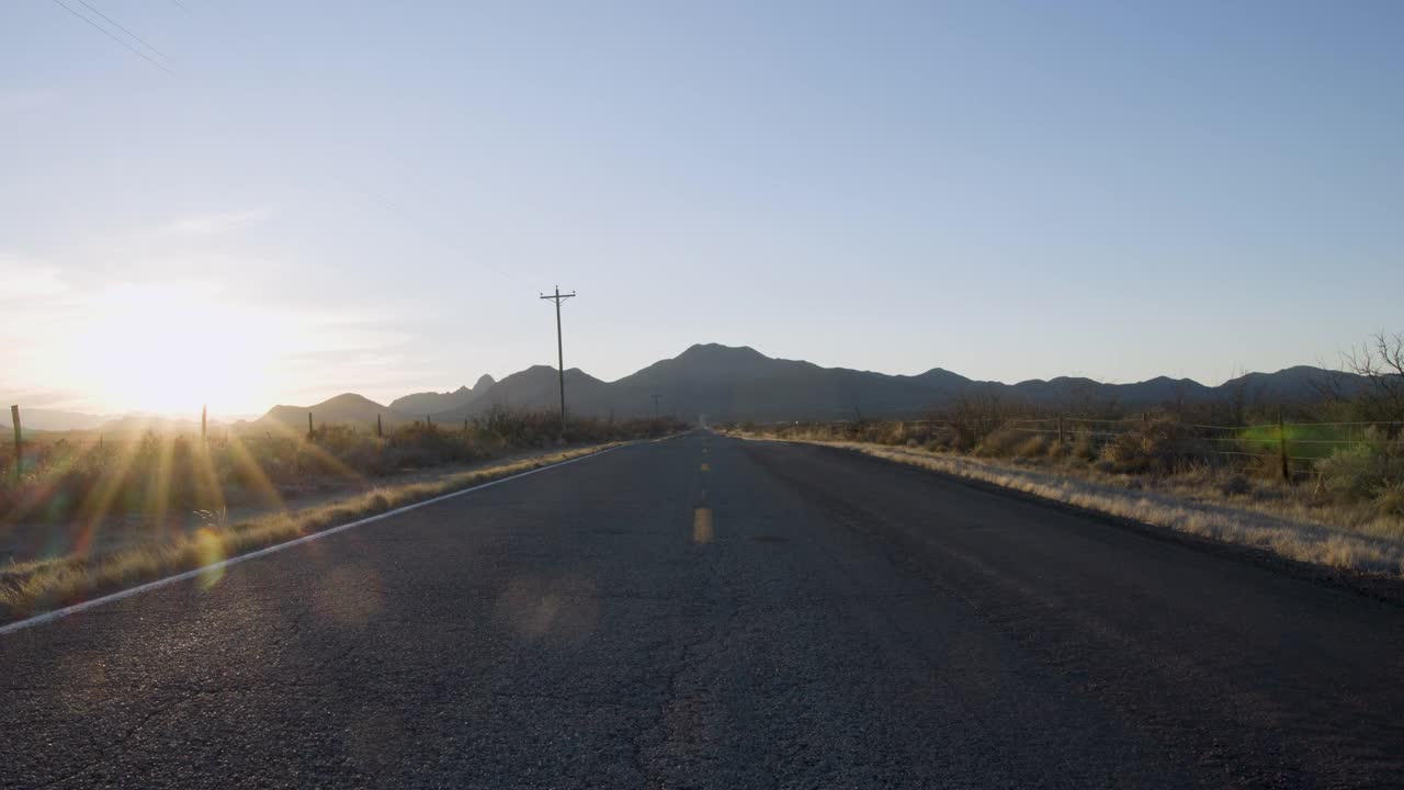 货车公路旅行旅行在沙漠山脉旁边的电线在一个开放的道路上日落视频下载