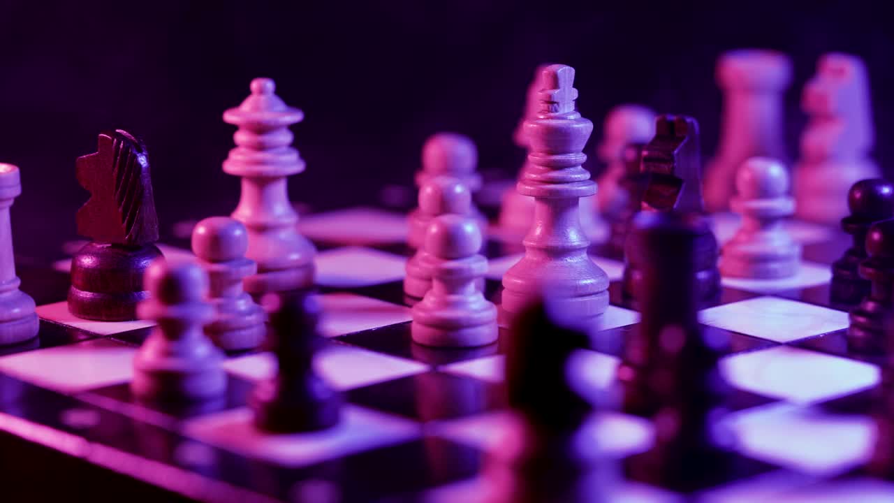 棋盘智力游戏-霓虹灯下的彩色灯光和烟雾下的木象棋。棋盘上的棋子在黑暗背景上的特写视图。商业解决方案，体育，成功战略概念。视频素材