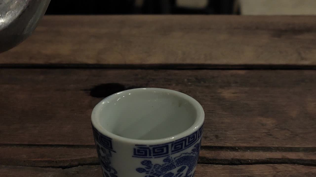 茶壶将热茶倒入玻璃杯中，产生白色蒸汽。视频素材