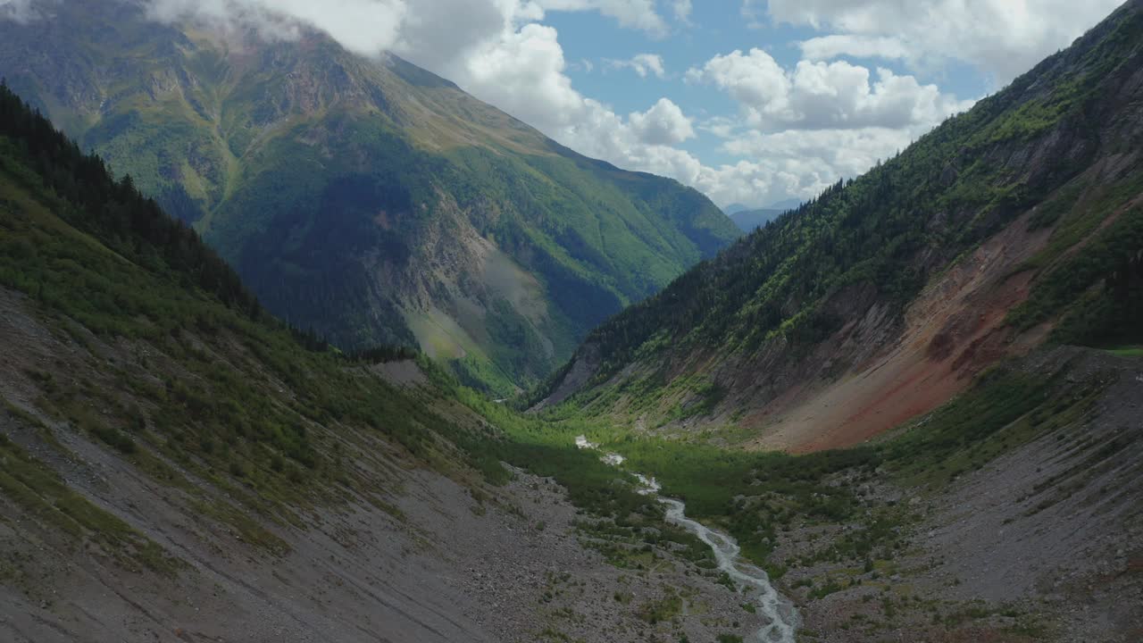 山溪在云雾笼罩的山峰间流动的鸟瞰图。视频下载