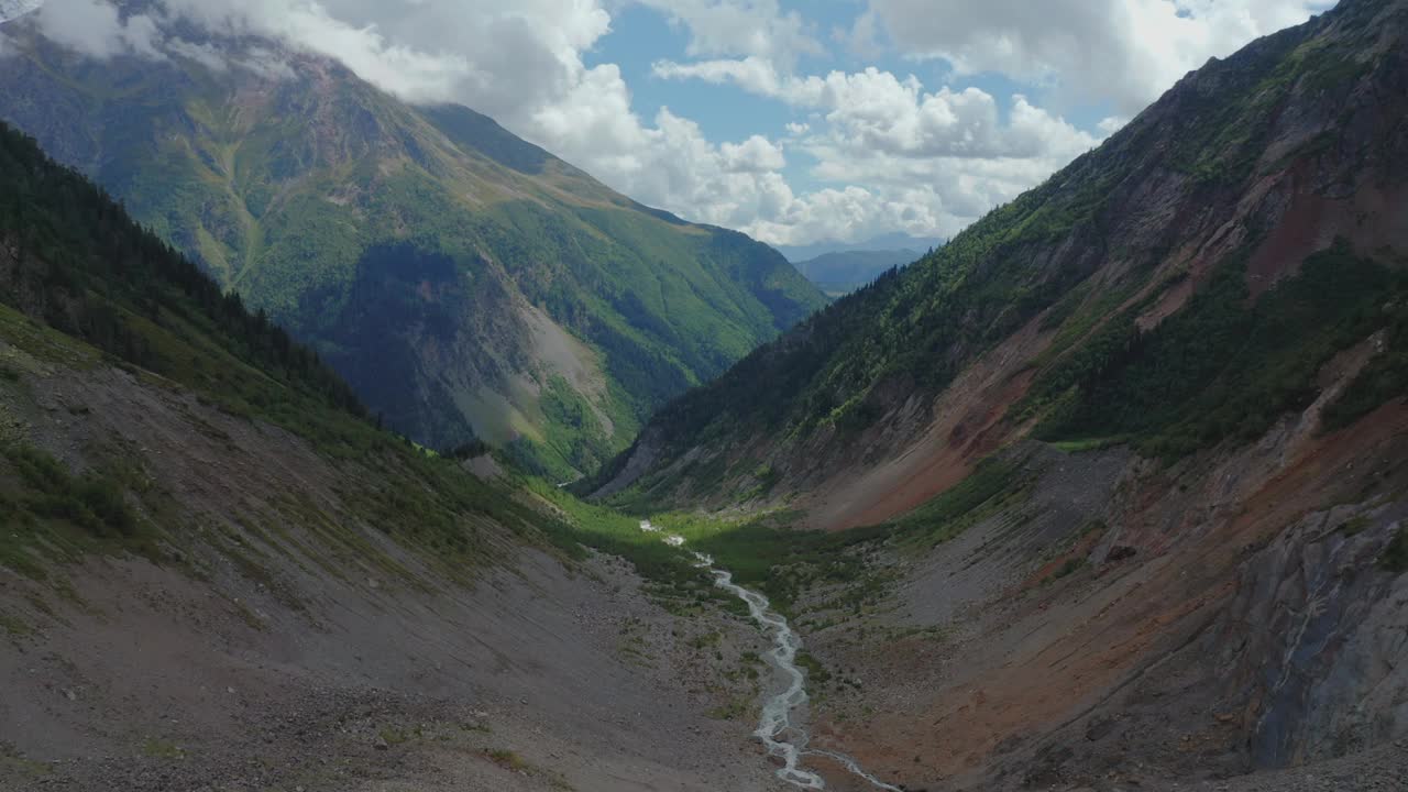 在云雾覆盖的山峰之间流动的山河的鸟瞰图。视频下载