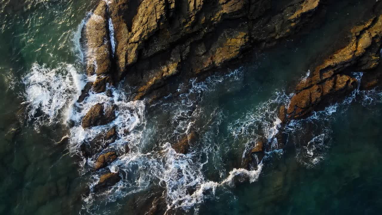 海水在明亮的阳光下撞击岩石。视频素材