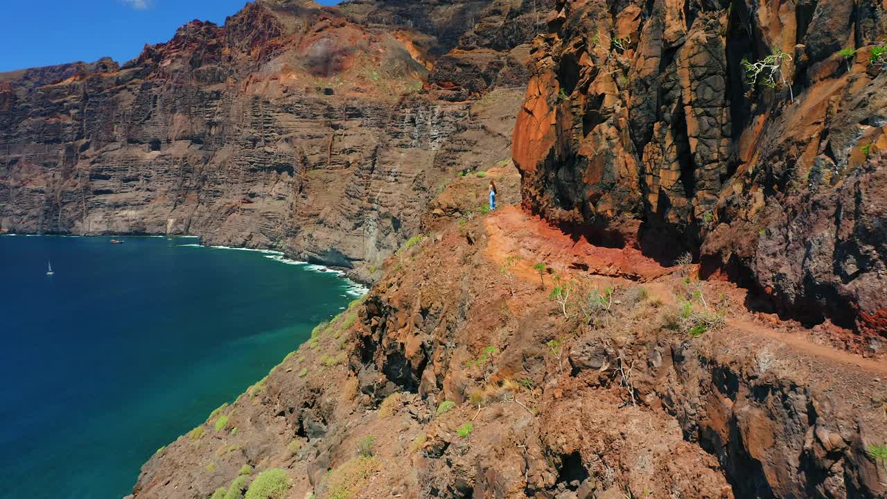 年轻女子在山上徒步旅行。海天线。夏季自然景观。女孩游客走在海边的悬崖上。女士羡慕热带的蓝色深海海景。积极的旅游生活方式。视频素材