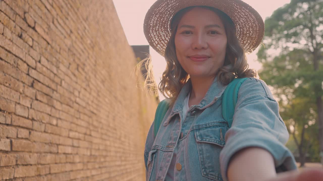 在泰国，一名女子用带稳定器的智能手机拍照和直播视频。视频博客。视频博客。街拍概念。视频素材