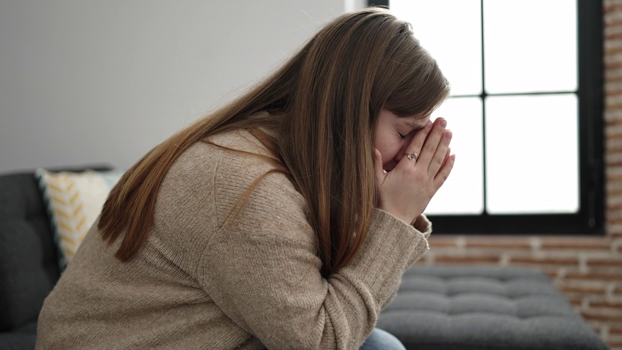 年轻的金发女子坐在家里的沙发上视频素材