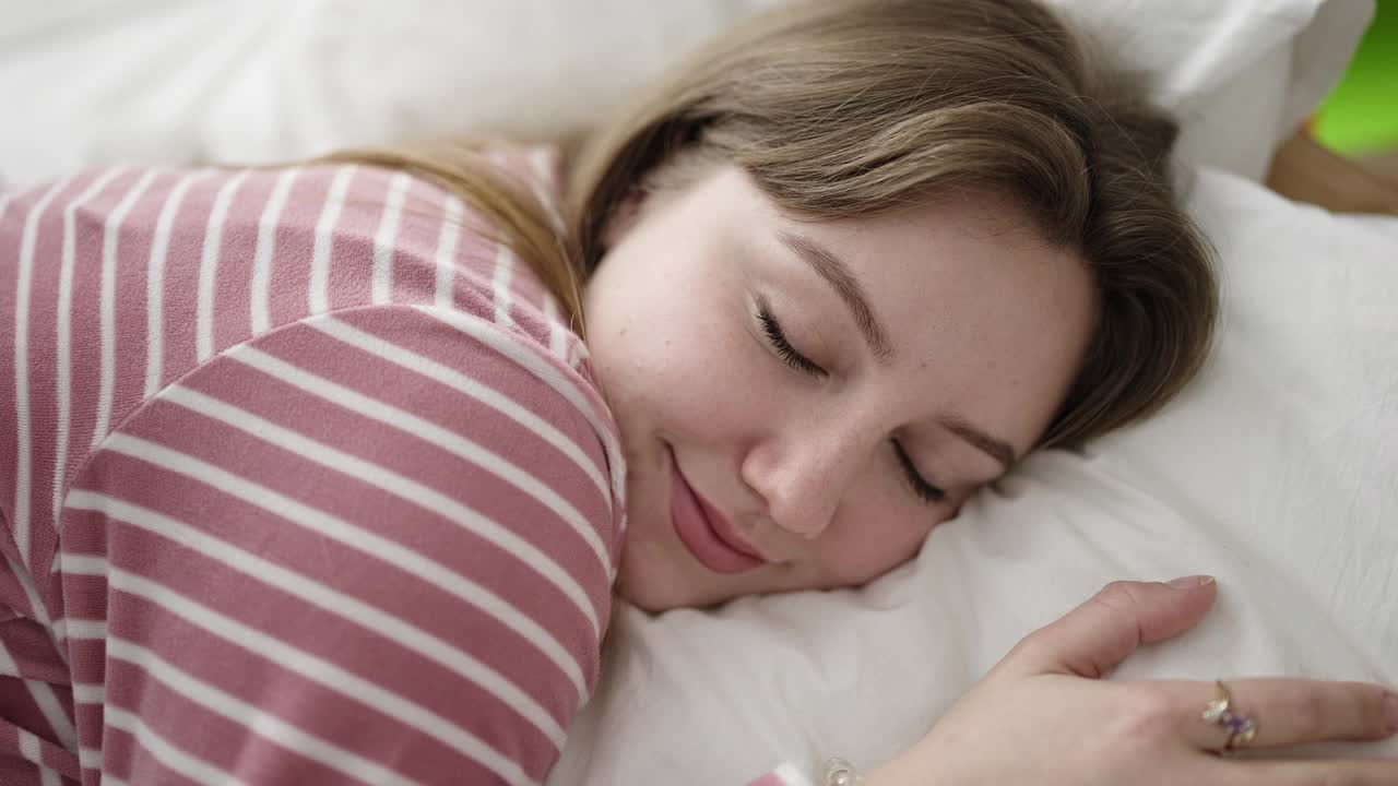 年轻的金发女子躺在床上睡觉在卧室里视频素材