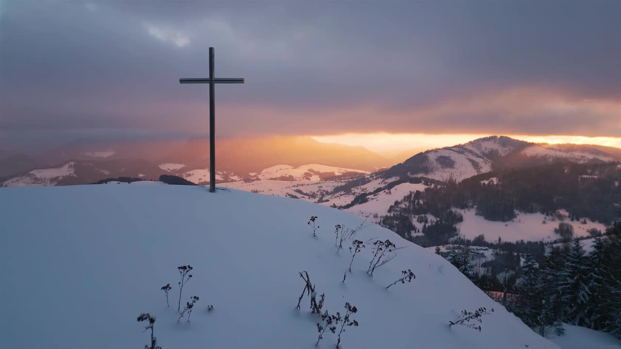 阳光在冬天乡村自然与钢十字架宗教基督教符号在雪山在日出鸟瞰视频素材