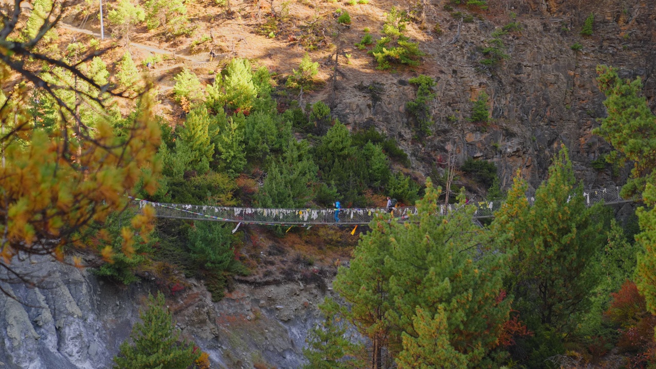 大型吊桥与佛教经幡在高山景观徒步旅行者穿越，尼泊尔安纳普尔纳赛道视频素材