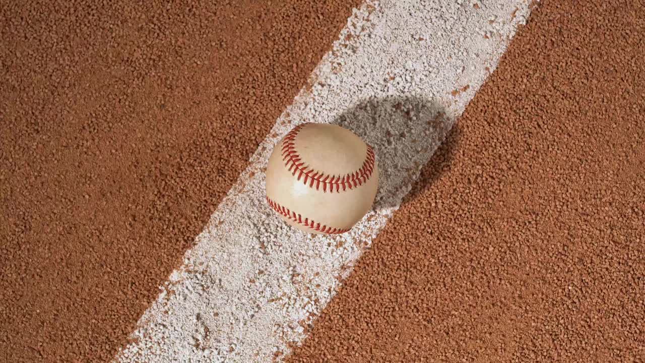 An overhead view of a baseball sitting on the infield baseline as the camera rotates – slow视频下载