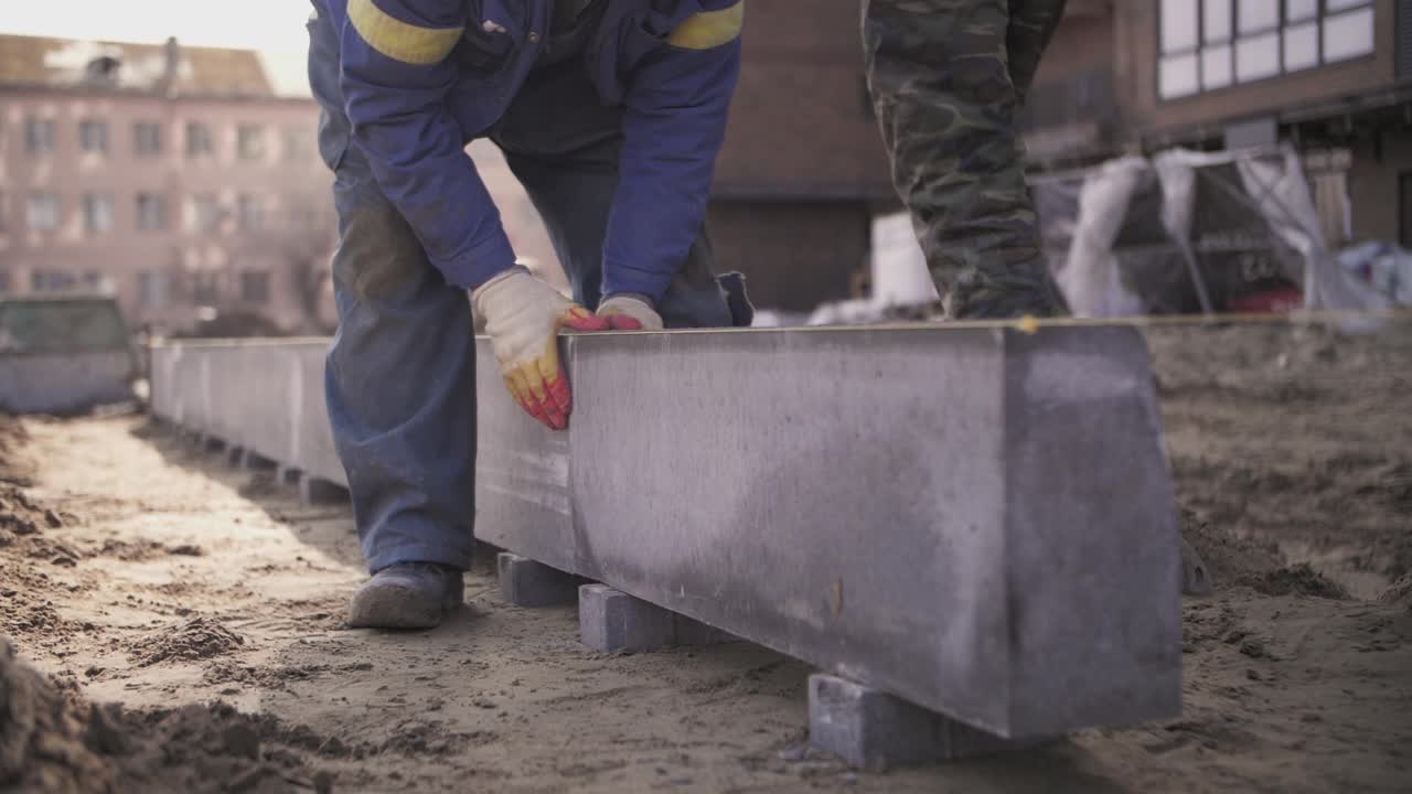 工人安装路缘。建筑工人在建筑工地工作视频素材