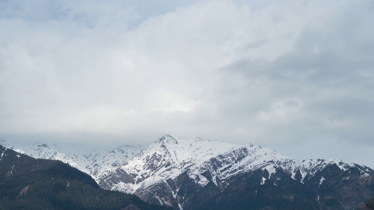 在印度喜马偕尔邦的马纳里，寒冷的冬天早晨，云在积雪覆盖的山上移动的4K时间推移。白雪皑皑的喜马拉雅山和多云的天空景观。自然背景。视频素材