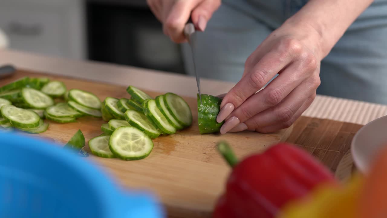 女性在餐桌上用刀切黄瓜。一名妇女正在烹饪健康的素食午餐，并在一个博卡什箱里堆肥果皮视频素材