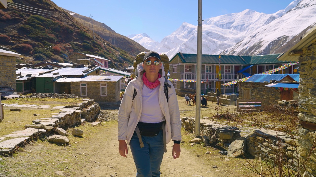 一名高加索女性徒步旅行者经过尼泊尔的一个传统村庄，Annapurna Circuit Trek视频素材