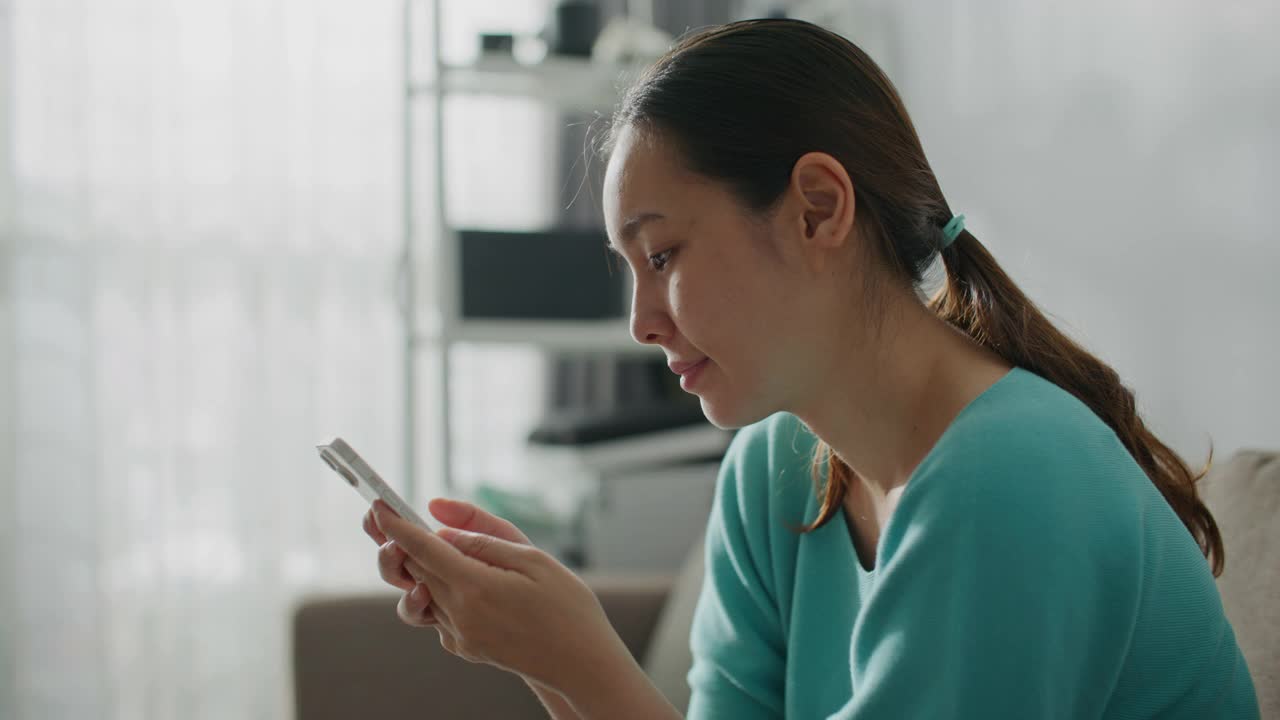 女人在家里的客厅里使用智能手机视频素材