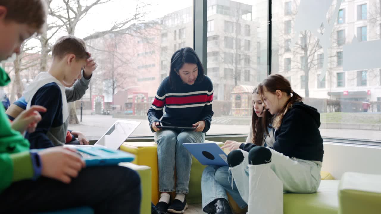 在儿童技术研讨会上，孩子们和老师坐在一起学习计算机视频下载