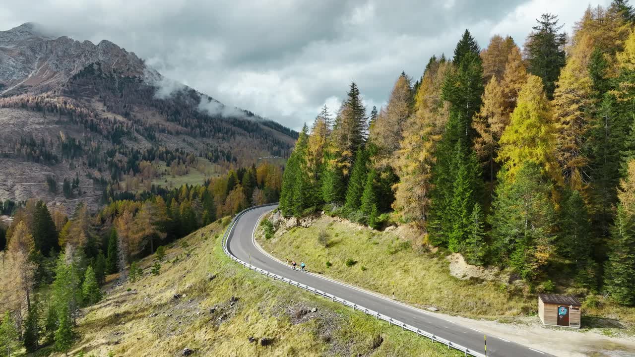 秋天的阿尔卑斯公路上两个人骑自行车的鸟瞰图视频素材