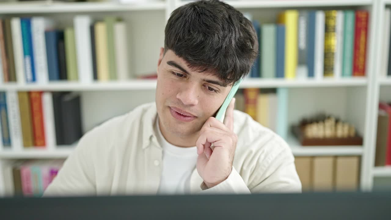 年轻的西班牙裔学生在图书馆大学学习，用智能手机与电脑交谈视频素材