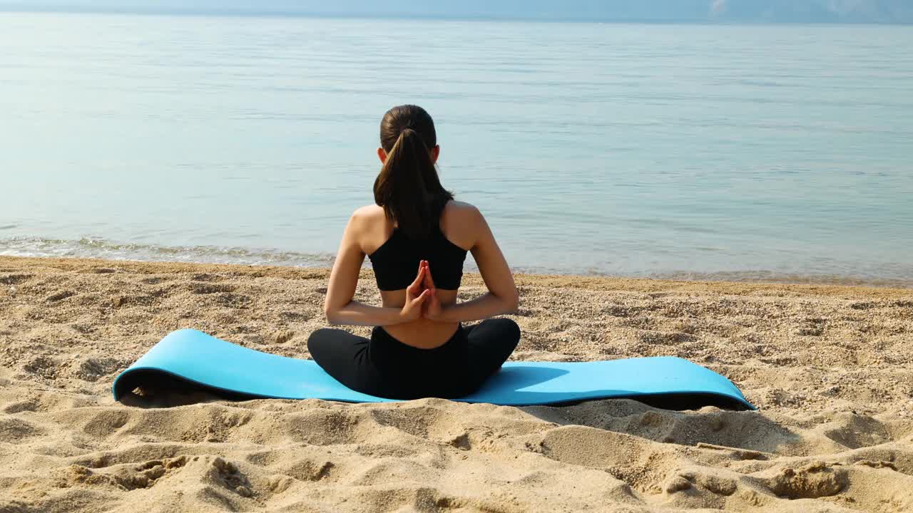 一个女孩在沙滩上做瑜伽。美丽的海景。冥想和休息。视频素材