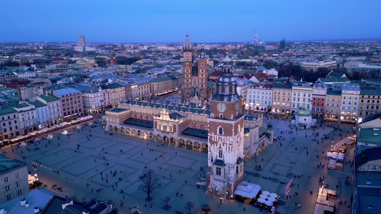 克拉科夫主要市场广场夜间无人机鸟瞰图。照明纪念碑:Mariacki(圣玛丽)教堂，Sukiennice(布厅)和市政厅塔视频素材