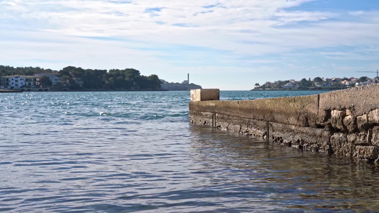 老渔夫码头，海浪在前面流动，远处的灯塔在背景上。视频下载