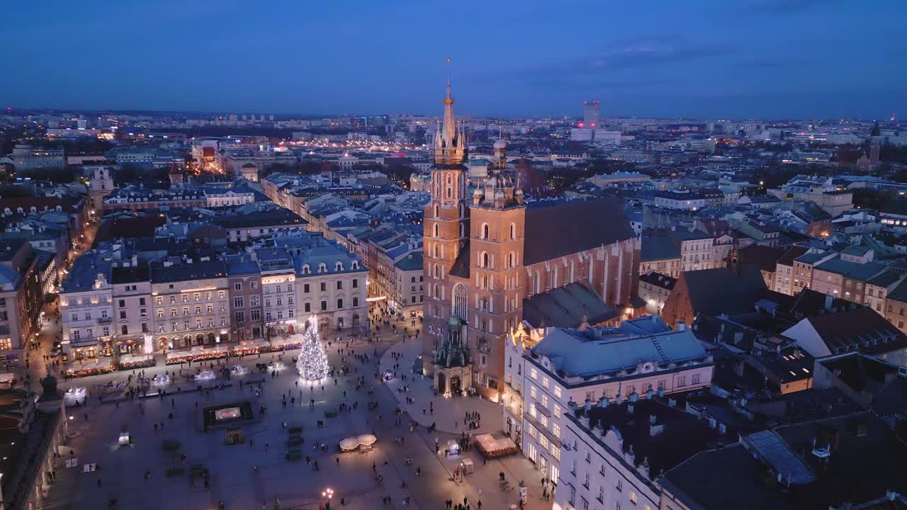 克拉科夫主要市场广场夜间无人机鸟瞰图。照明纪念碑:Mariacki(圣玛丽)教堂，Sukiennice(布厅)和市政厅塔视频素材