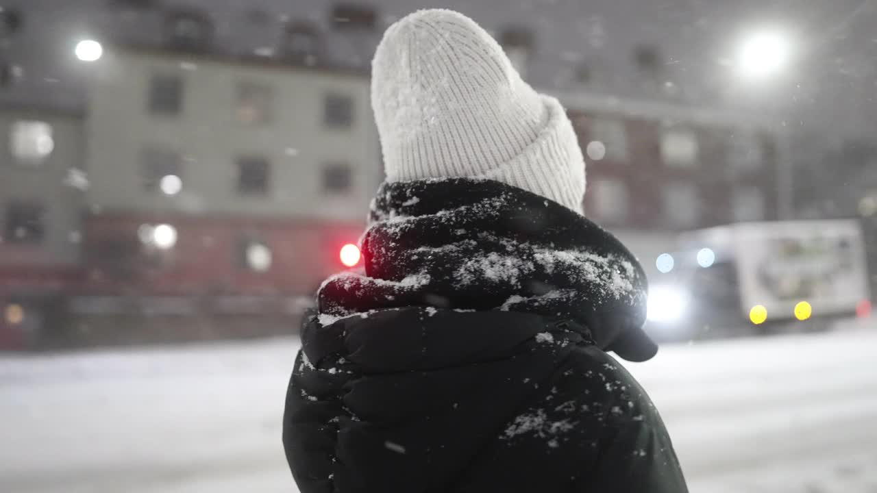 一个女人站在城市里，看着雪视频素材