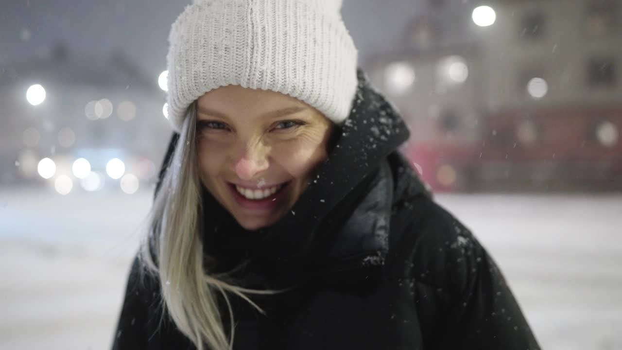 一个快乐的女人的肖像在一个雪夜，在城市视频素材