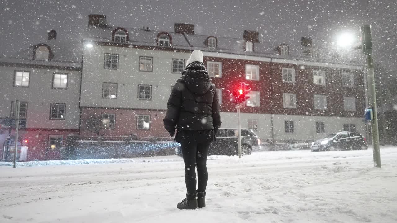 一个女人站在城市里，看着雪视频素材