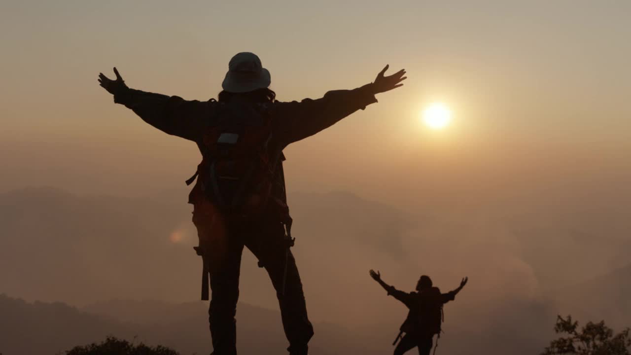 两个旅行者在悬崖上举起手。视频素材