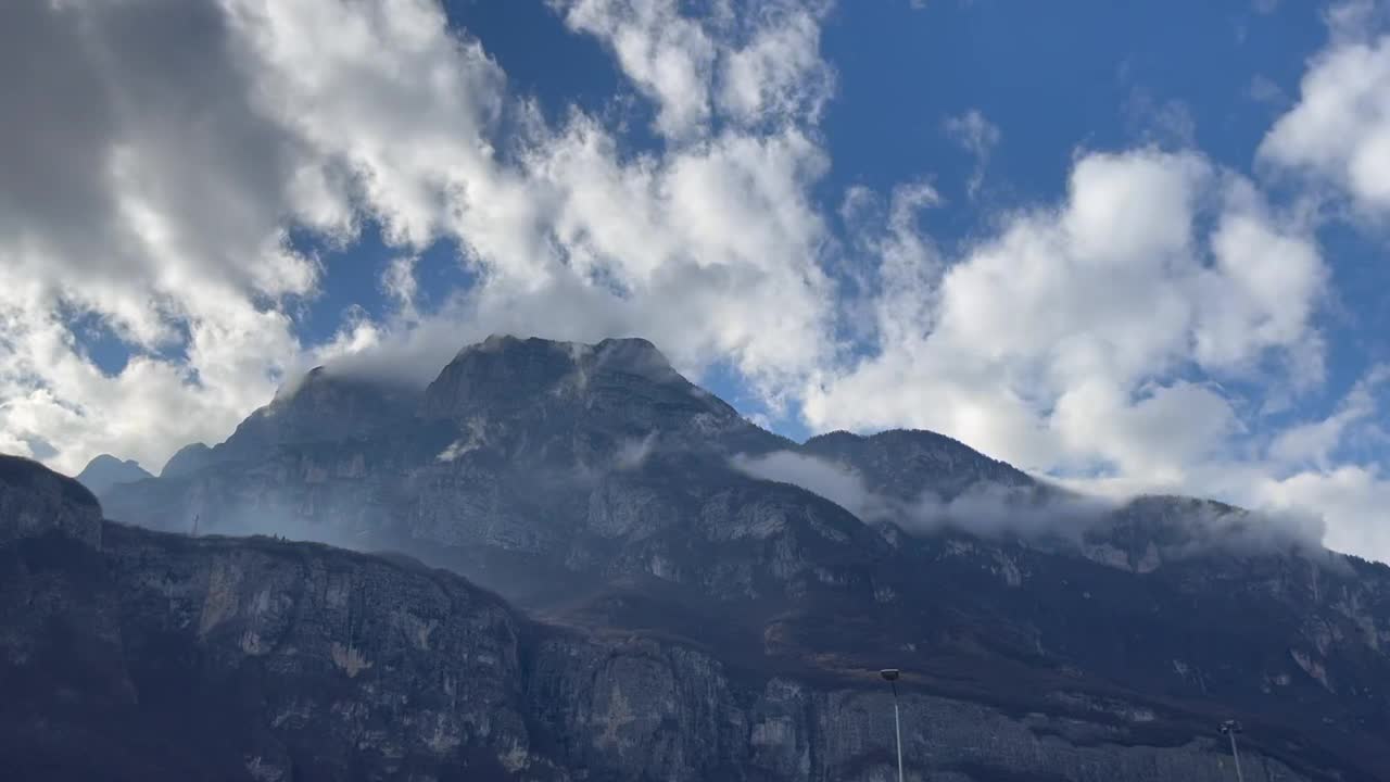 低垂的云层穿过巍峨的群山，映衬着多云的蓝天视频下载