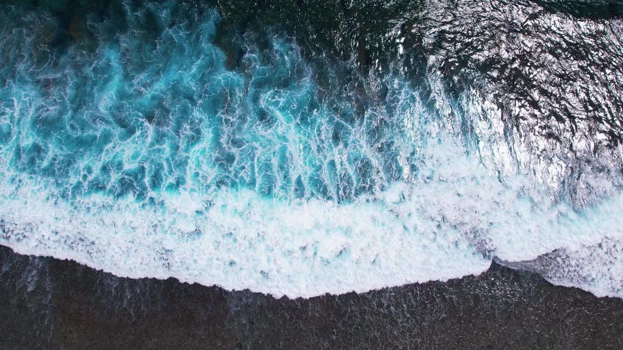 海浪滚滚而来。从上到下4k无人机视角，蓝色蓝绿色的海洋，慢镜头。巨大的海浪冲击着海岸线。印尼巴厘岛视频素材