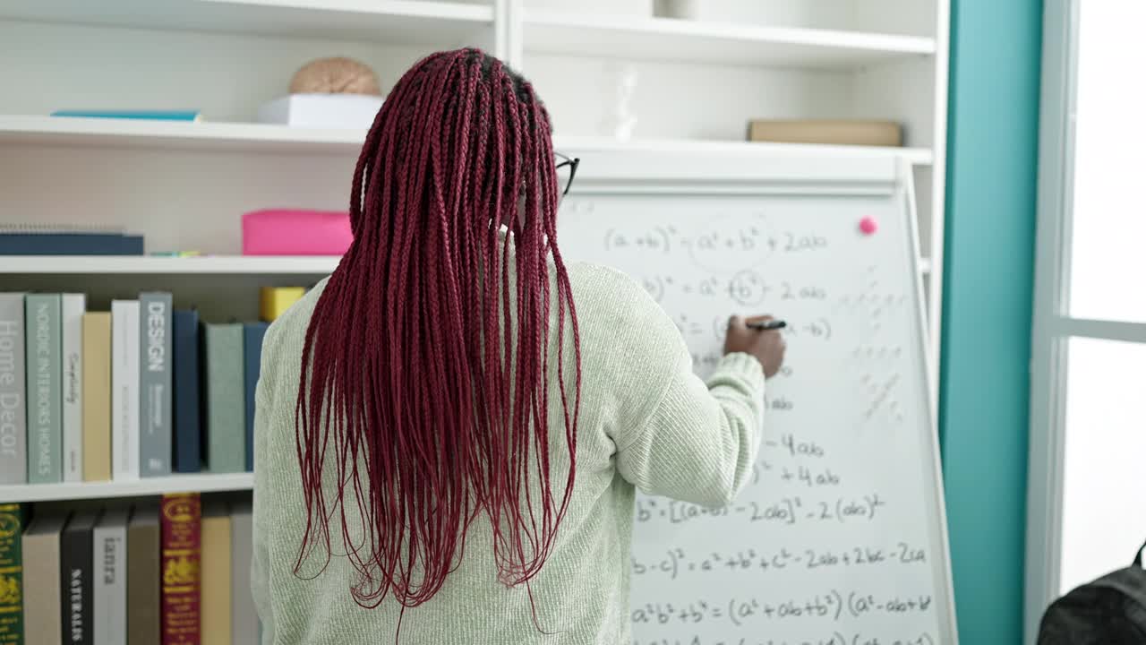 一个梳着辫子的非洲女人站在大学图书馆的白板前微笑视频素材