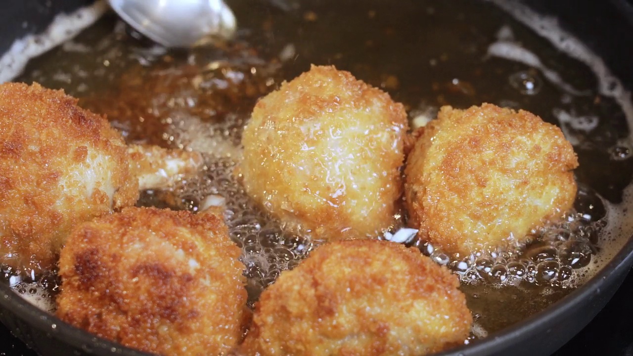 准备食物。用油炸锅准备鸡块。在滚烫的油中煎鸡的过程。在家煎美味的炸鸡。有选择性的重点。慢动作视频视频素材