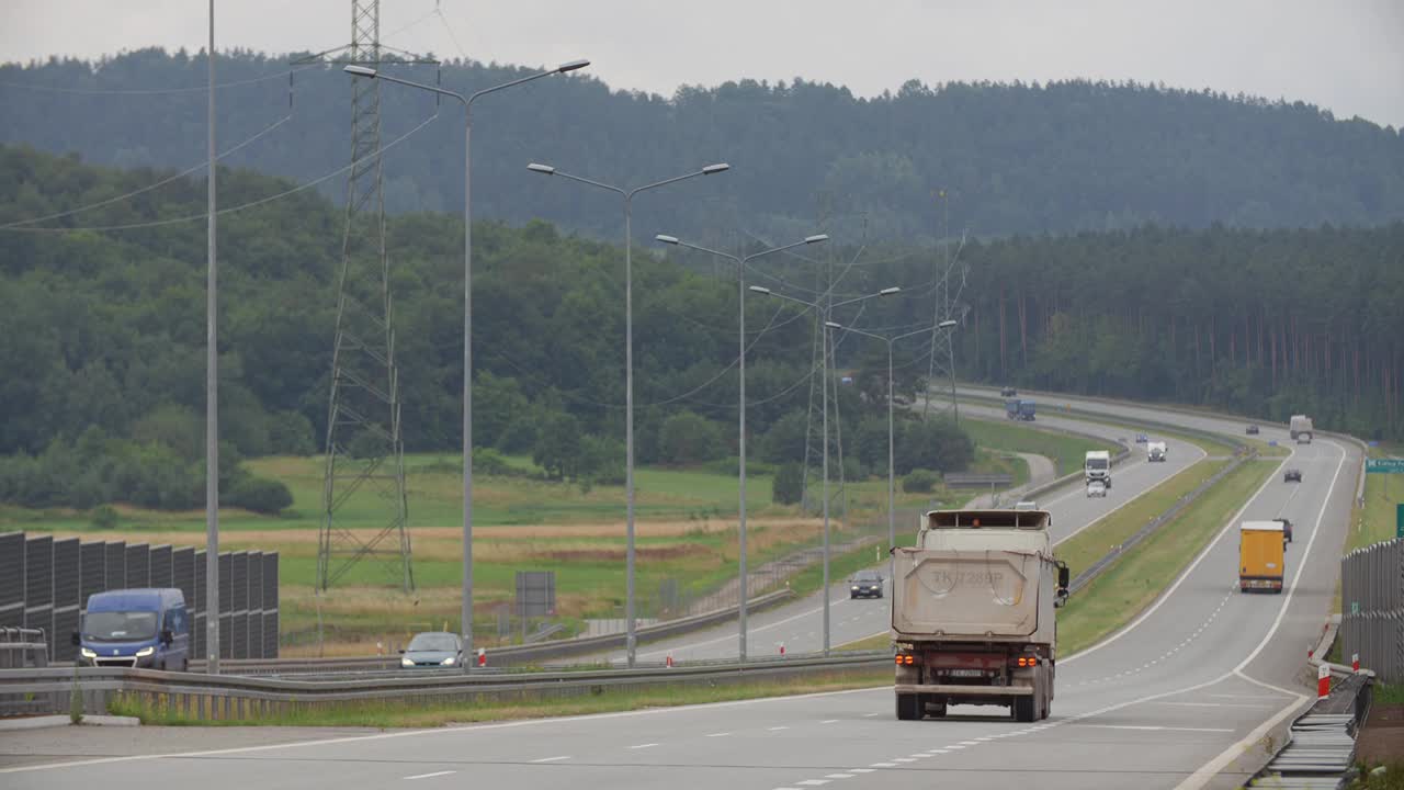 现代高速公路行驶轿车和重型卡车，丘陵景观阴天视频素材