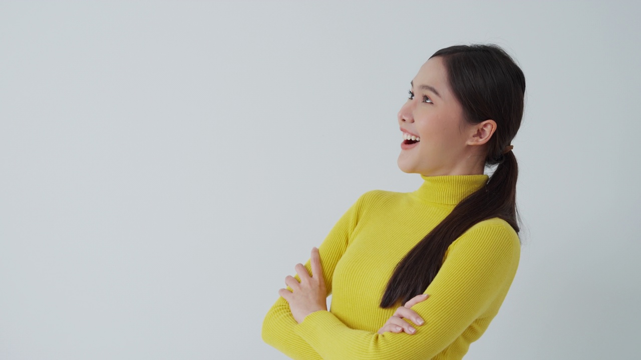 肖像亚洲美丽的女孩看空白空间孤立的背景。快乐的女人看东西。年轻女性站着，手指向旁边，广告牌，介绍，广告，空间视频素材