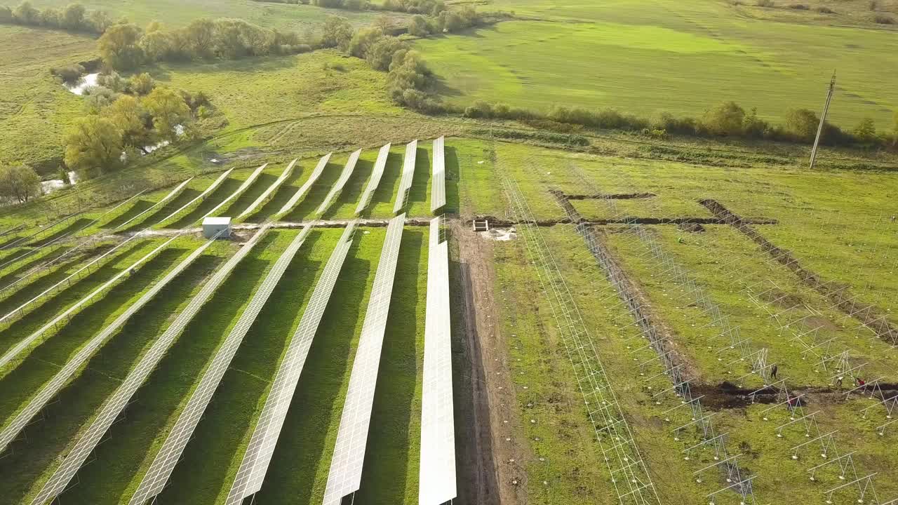 绿色土地上正在建设的太阳能发电厂鸟瞰图。用于生产清洁生态能源的电板组装。视频素材