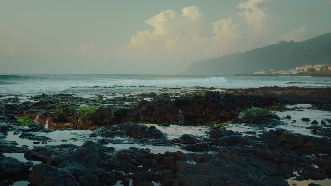 海浪冲击着特内里费岛海岸的黑色火山岩。深蓝色的海浪猛烈地拍打着一个异域岛屿的岩石海岸。视频素材