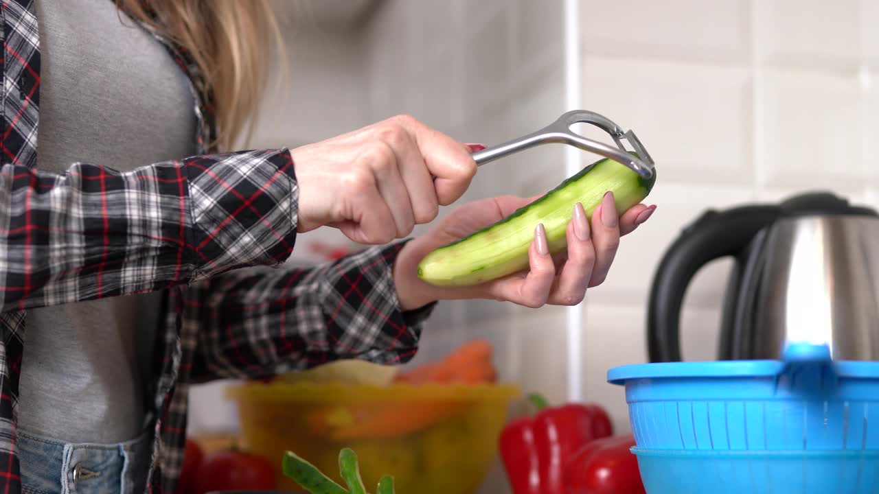 家庭主妇用削皮工具削黄瓜皮。女性在家做健康的素食沙拉视频素材