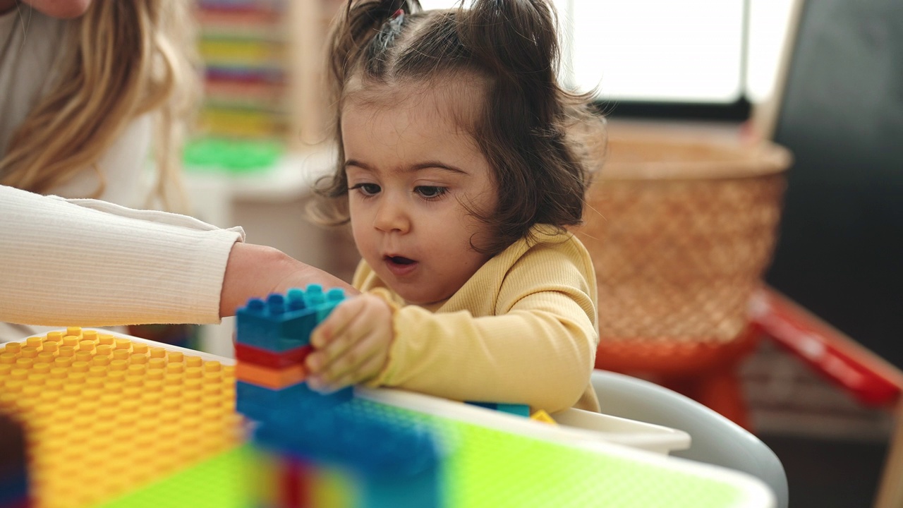 幼儿园里，老师和孩子坐在桌子上玩积木视频素材