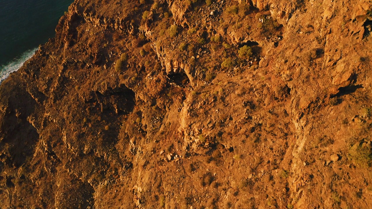 陡峭的悬崖，沙漠火山山脉形成了西班牙加那利群岛特内里费岛的海岸线。Los Gigantes的岩石有着深蓝色的海水。日落时电影般的空中飞行。视频素材