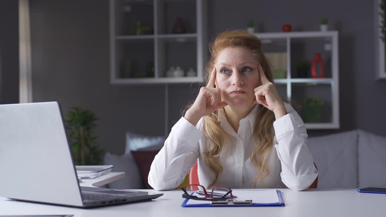 一位在家庭办公室工作的老年女商人正在思考创造性的想法。视频素材