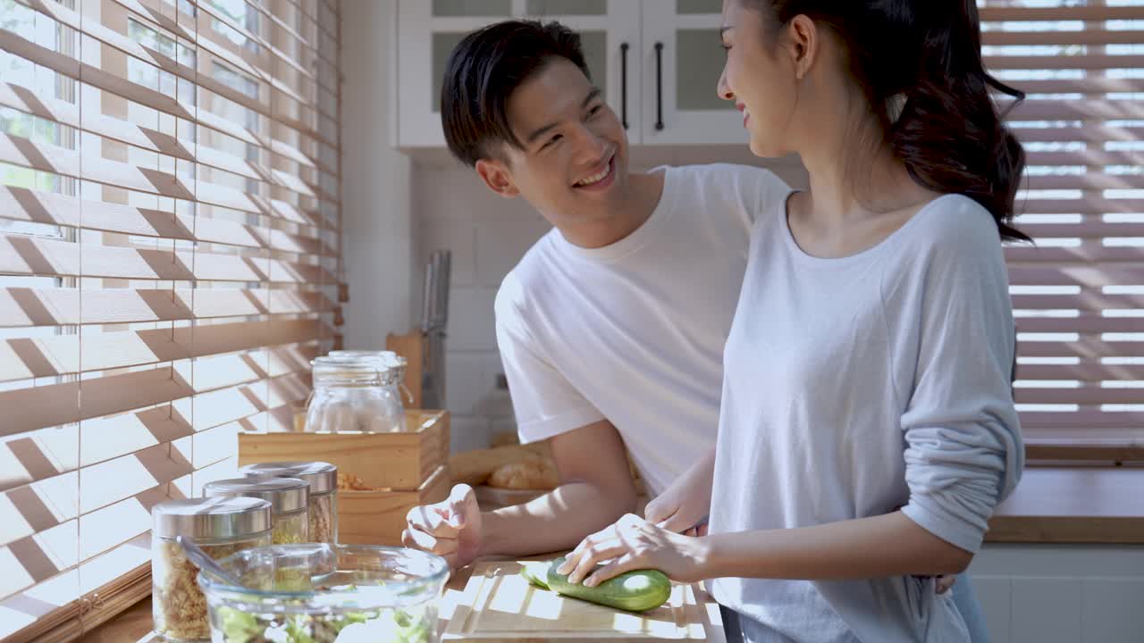 快乐的亚洲夫妇在厨房准备食物时玩得很开心。视频素材