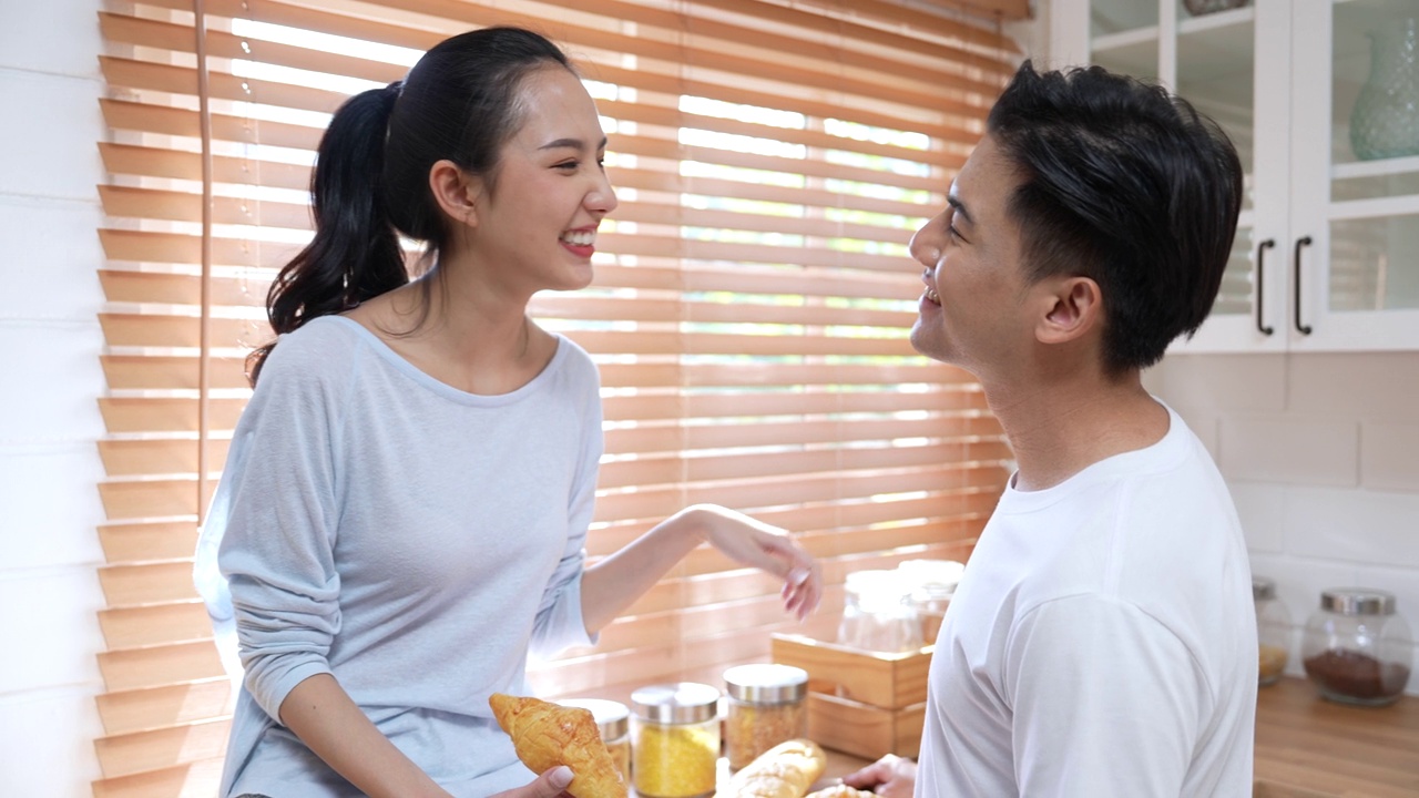 幸福的年轻夫妇在厨房里互相喂食。视频素材