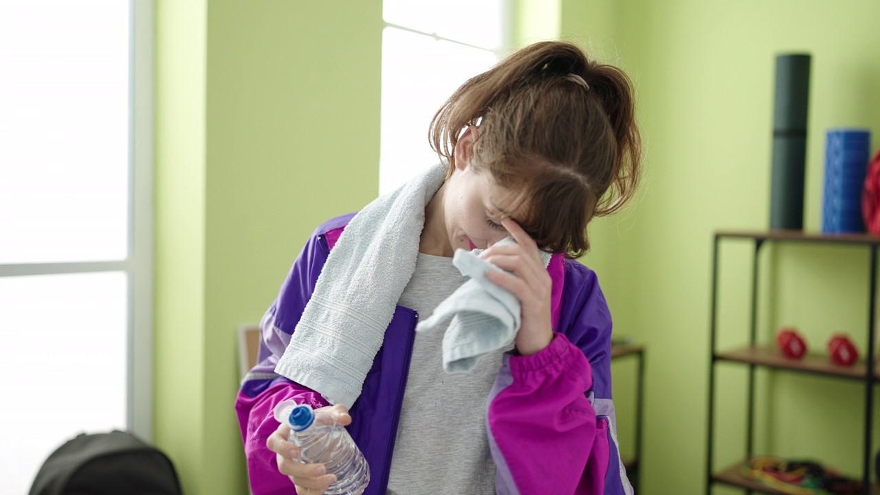 年轻的白人妇女在运动中心喝水视频素材