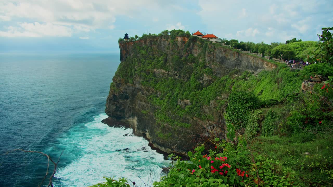 原始的热带绿色海滩与Uluwatu寺庙Pura Luhur印度教在巨大的悬崖深渊和无尽的海洋地平线在巴厘岛。暑假放假。巴厘岛的海水和岩石海岸线。视频素材